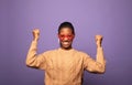 Young African American woman celebrates victory and success, feels lively and energetic over purple background