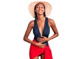 Young african american woman wearing swimsuit and summer hat smiling and laughing hard out loud because funny crazy joke with Royalty Free Stock Photo