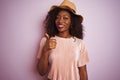 Young african american woman wearing t-shirt and hat over isolated pink background doing happy thumbs up gesture with hand Royalty Free Stock Photo