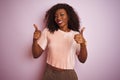 Young african american woman wearing t-shirt standing over isolated pink background success sign doing positive gesture with hand, Royalty Free Stock Photo