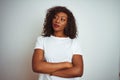 Young african american woman wearing t-shirt standing over isolated white background looking to the side with arms crossed Royalty Free Stock Photo