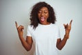 Young african american woman wearing t-shirt standing over isolated white background shouting with crazy expression doing rock Royalty Free Stock Photo