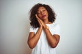 Young african american woman wearing t-shirt standing over  white background sleeping tired dreaming and posing with hands Royalty Free Stock Photo