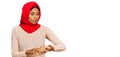 Young african american woman wearing traditional islamic hijab scarf checking the time on wrist watch, relaxed and confident Royalty Free Stock Photo