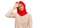 Young african american woman wearing traditional islamic hijab scarf making fun of people with fingers on forehead doing loser Royalty Free Stock Photo