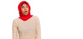 Young african american woman wearing traditional islamic hijab scarf in shock face, looking skeptical and sarcastic, surprised