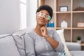 Young african american woman wearing virtual reality glasses sitting on the sofa thinking concentrated about doubt with finger on Royalty Free Stock Photo