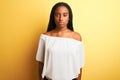 Young african american woman wearing white t-shirt standing over  yellow background with serious expression on face Royalty Free Stock Photo