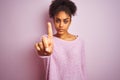 Young african american woman wearing winter sweater standing over isolated pink background Pointing with finger up and angry Royalty Free Stock Photo