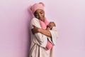 Young african american woman wearing wool hat and winter scarf hugging oneself happy and positive, smiling confident Royalty Free Stock Photo