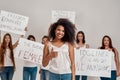 Young african american woman in white shirt showing OK sign, smiling at camera. Group of diverse women holding protest Royalty Free Stock Photo