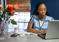 Young, African American woman working from home on her laptop in the kitchen Royalty Free Stock Photo