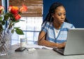 Young, African American woman working from home on her laptop in the kitchen Royalty Free Stock Photo