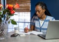 Young, African American woman working from home on her laptop in the kitchen