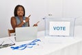 Young african american woman working at political election sitting by ballot pointing aside worried and nervous with both hands, Royalty Free Stock Photo