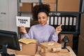 Young african american woman working at small business ecommerce holding thank you banner smiling happy pointing with hand and Royalty Free Stock Photo