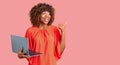 Young african american woman working using computer laptop pointing thumb up to the side smiling happy with open mouth Royalty Free Stock Photo