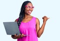 Young african american woman working using computer laptop pointing thumb up to the side smiling happy with open mouth Royalty Free Stock Photo