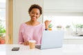 Young african american woman working using computer laptop smiling with happy face looking and pointing to the side with thumb up Royalty Free Stock Photo