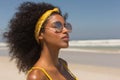 Young African American woman in yellow bikini and sunglasses standing on the beach Royalty Free Stock Photo