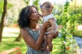 Young african american woman and her daughter walking in summer park. Black mother playing with her baby girl outdoors. Cute baby Royalty Free Stock Photo