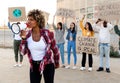 African American woman shouting through megaphone leading demonstration protesting against climate change.