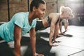 Smiling young woman doing pushups with friends at the gym