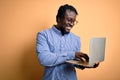 Young african american worker man working using laptop standing over yellow background with a happy face standing and smiling with Royalty Free Stock Photo