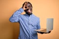 Young african american worker man working using laptop standing over yellow background with happy face smiling doing ok sign with Royalty Free Stock Photo