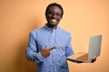 Young african american worker man working using laptop standing over yellow background very happy pointing with hand and finger Royalty Free Stock Photo