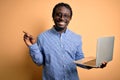 Young african american worker man working using laptop standing over yellow background very happy pointing with hand and finger to Royalty Free Stock Photo