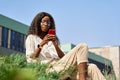 Young African black happy woman using mobile apps on cell phone outside. Royalty Free Stock Photo