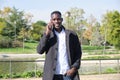 Young african black man speaking and smiling on the smartphone looking at camera in a park Royalty Free Stock Photo