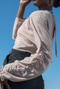 Young african black model posing showing details of a white blouse. Fashionable shot against a blue sky