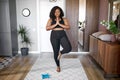 Young african woman keep balance, stand on one leg, yoga time at home