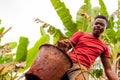 Young african boy with bucket full of soil during manual digging of water well in african country with effort expression on his Royalty Free Stock Photo