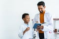 Young African boy in a white lab coat learns about an experimental error in blue textbook after a teacher teaches how to correct