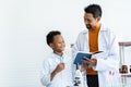 A young African boy in white lab coat understand about mistake experiment information in blue textbook after teacher Royalty Free Stock Photo