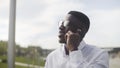 Young African Businessman with braces talking on cell phone in city park Royalty Free Stock Photo