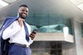 Young african businessman holding his phone while standing full of joy Royalty Free Stock Photo