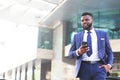 Young african businessman leaving the office full of satisfaction while using his phone. Copy space Royalty Free Stock Photo