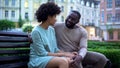 Young african couple cuddling on bench at sunset, date in city park, closeness Royalty Free Stock Photo