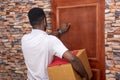 Young African courier knocking on a door Royalty Free Stock Photo