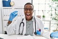 Young african doctor man holding syringe at the hospital angry and mad screaming frustrated and furious, shouting with anger Royalty Free Stock Photo