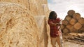 Young african farmer resting on the fork handle in front of hay roll stack