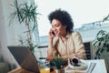 Young African female entrepreneur sitting at a desk in her home office working online with a laptop Royalty Free Stock Photo