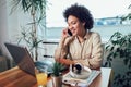 Young African female entrepreneur sitting at a desk in her home office working online with a laptop Royalty Free Stock Photo