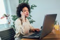 Young African female entrepreneur sitting at a desk in her home office working online with a laptop Royalty Free Stock Photo