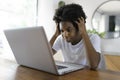 young African female entrepreneur working online with a laptop while sitting at her kitchen table at home look sad Royalty Free Stock Photo