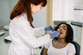 Young African female patient at dental office, opening mouth while smiling woman dentist in uniform and blue latex Royalty Free Stock Photo